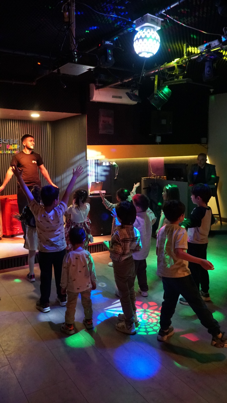 Children dancing under disco lights with an entertainer at Bonjur mini disco, Ümraniye