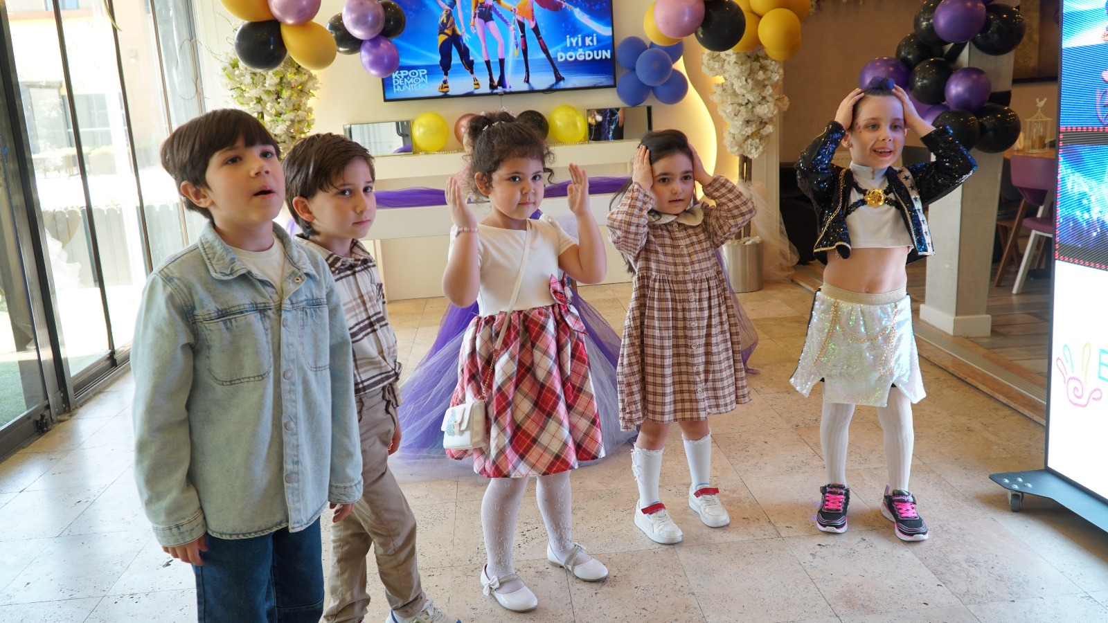 Mor ve altın balonlarla temalı süslenmiş salonda dans eden çocuklar, Bonjur parti evi