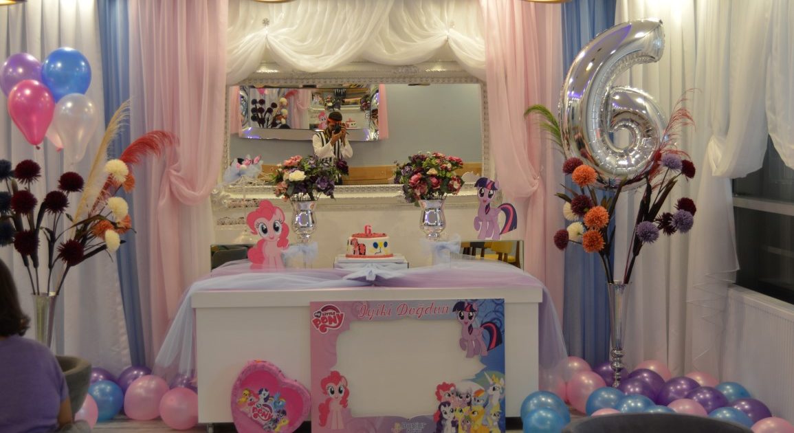 A pony-themed birthday table decorated with balloons, flowers and a silver number 6 balloon